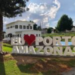 Placa 'Eu Amo Porto Amazonas' com edifício ao fundo.